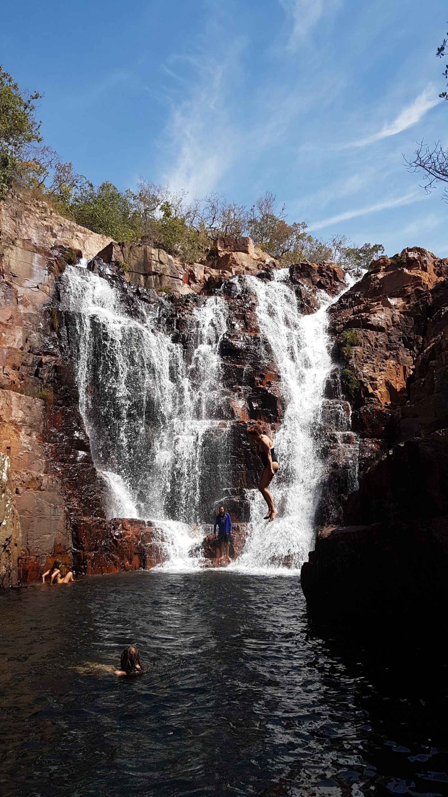 Cachoeira da Escadaria com diversas pessoas descansando e um homem saltando, na Chapada dos Veadeiros, complexo macaco