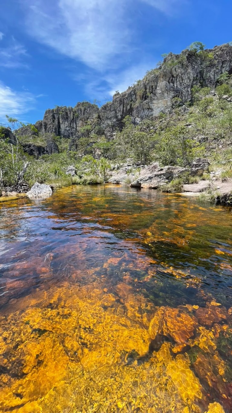 Águas douradas e cristalinas do Poço Xamânico na trilha da Ponte de Pedra
