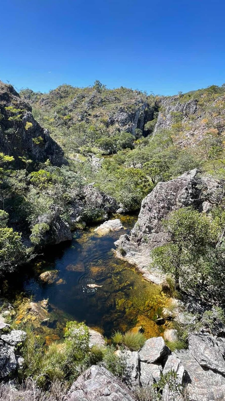 Turista nadando no Poço Xamânico entre paredões rochosos na trilha da Ponte de Pedra, Cavalcante