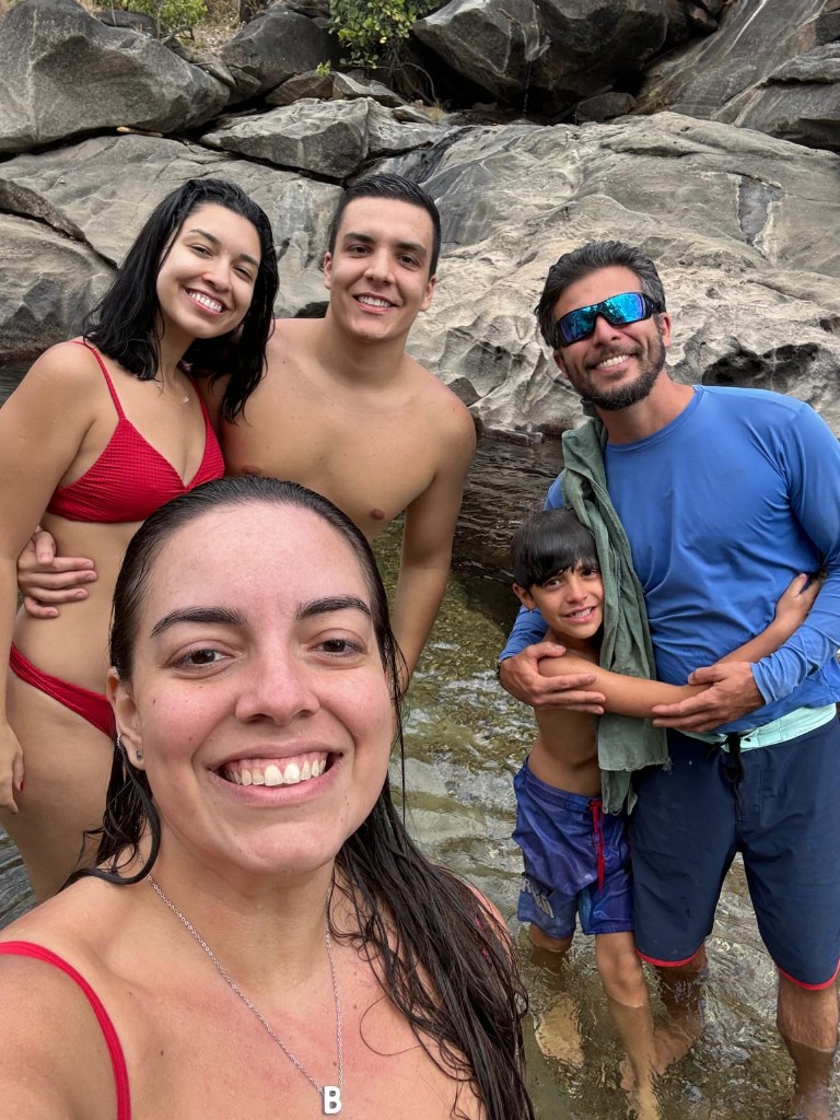 Guia e família em poça natural entre rochas na Chapada dos Veadeiros — experiência humana do turismo com condutor local
