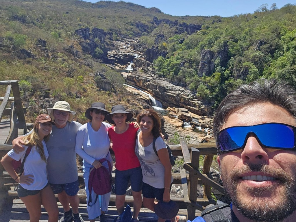 Grupo multigeracional com guia em mirante de madeira sobre canyon e trecho de rio na Chapada dos Veadeiros