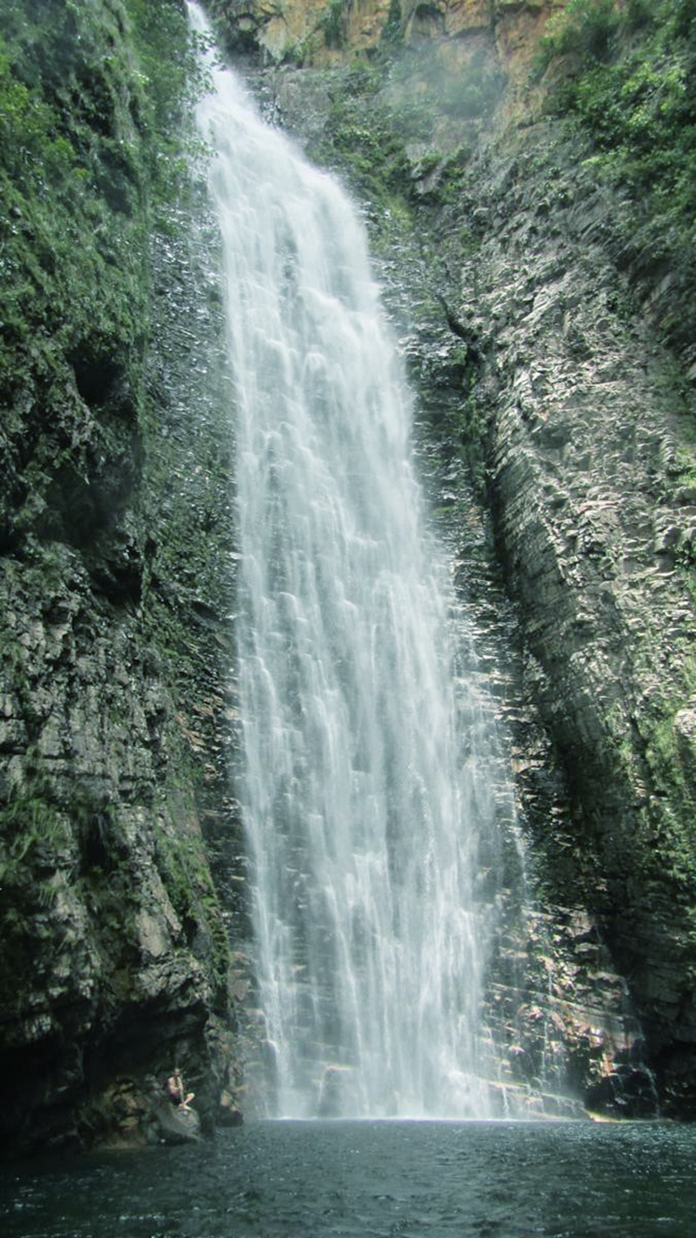 Cachoeira do Segredo em São Jorge na Chapada dos Veadeiros durante o período de chuvas, com vazão máxima e água branca descendo pela parede de rocha coberta de vegetação verde